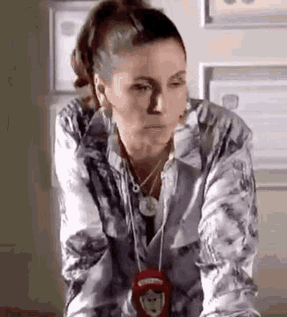a woman wearing a necklace and a police badge is sitting at a table .
