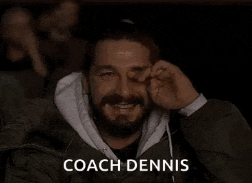 a man with a beard is covering his nose while watching a movie in a theater .
