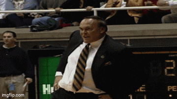 a man in a suit and tie is standing in front of a scoreboard that says 2