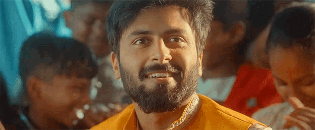 a man with a beard is smiling in front of a crowd of children
