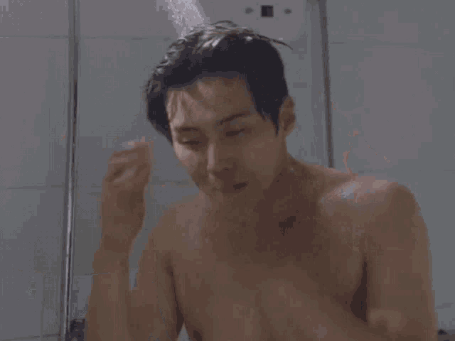 a shirtless man is taking a shower without a shirt on