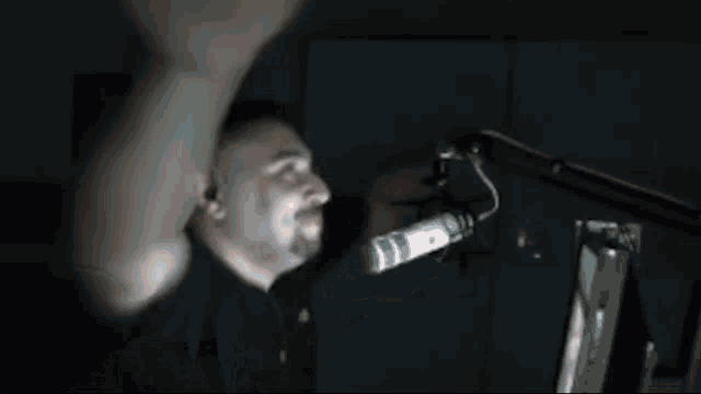 a man is singing into a microphone with his hands in the air