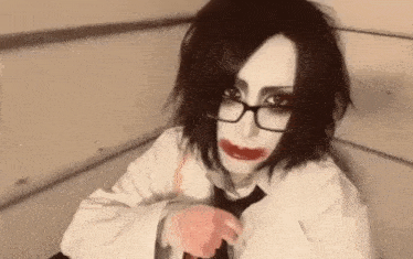 a woman wearing glasses and a white shirt and tie is sitting on a couch .