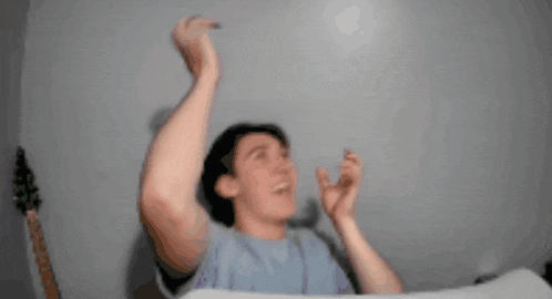 a man in a blue shirt is making a funny face with his arms outstretched
