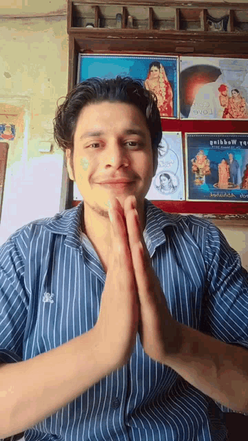 a man wearing a blue striped shirt has his hands folded in front of him