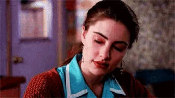 a close up of a woman wearing a blue shirt and a red sweater