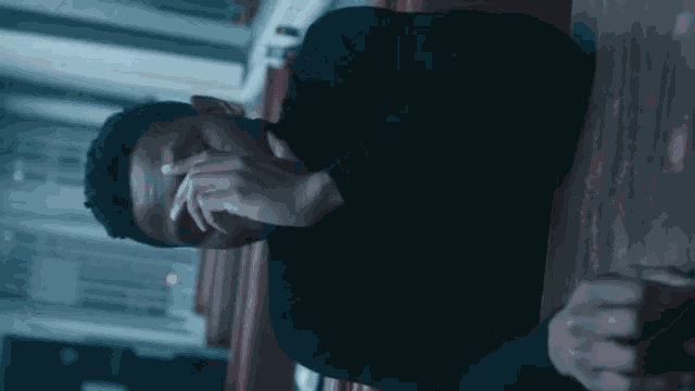 a man in a black shirt covering his face with his hands