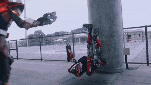 a person in a superhero costume is doing a handstand next to a fence