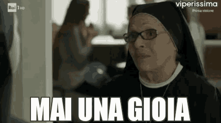 a nun wearing glasses and a head scarf is standing in front of a wall .