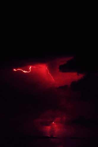 a red lightning bolt strikes the ground in the night sky