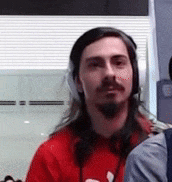 a man with long hair is wearing headphones and a red shirt .