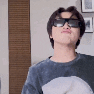 a young man wearing sunglasses and a shark shirt is making a face .