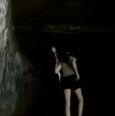 a woman is standing in a dark room playing a guitar