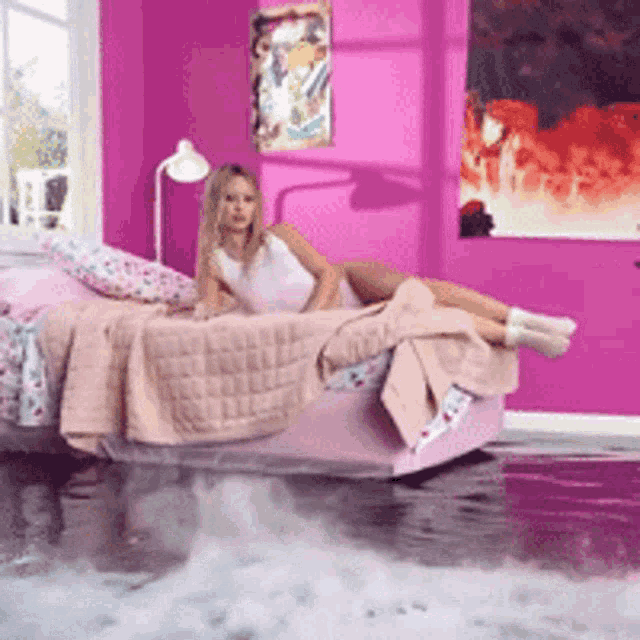 a woman is laying on a bed in a flooded room