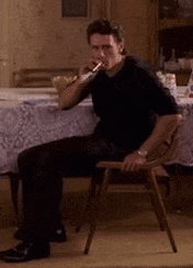 a man in a black shirt is sitting in a chair and smoking a cigarette
