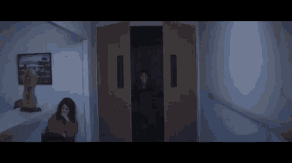a woman in a red sweater is sitting in a dark hallway