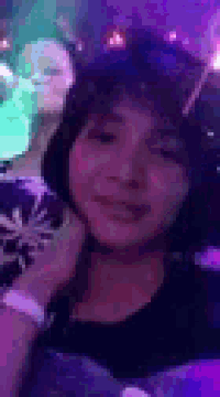 a close up of a woman 's face in a club with purple lights behind her .