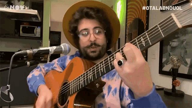 a man is playing a guitar in front of a microphone with the hashtag #otalabnouol on the bottom