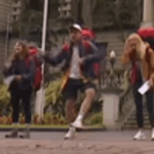 a group of people are standing on a sidewalk with backpacks .
