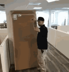 a man is carrying a large cardboard box in a hallway