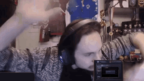 a man wearing headphones is playing a video game in front of a screen that says league of legends on it