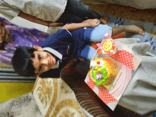 a boy laying on a couch next to a birthday cake that says happy birthday