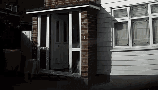a white house with a porch and a brick building .