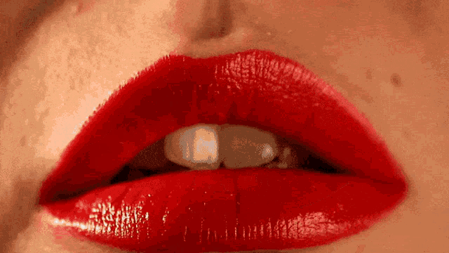 a close up of a woman 's mouth with red lipstick and white teeth .