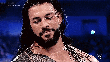 roman reigns is a wrestler with a beard and long hair and is wearing a wrestling ring belt .
