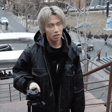 a man in a black leather jacket is holding a camera
