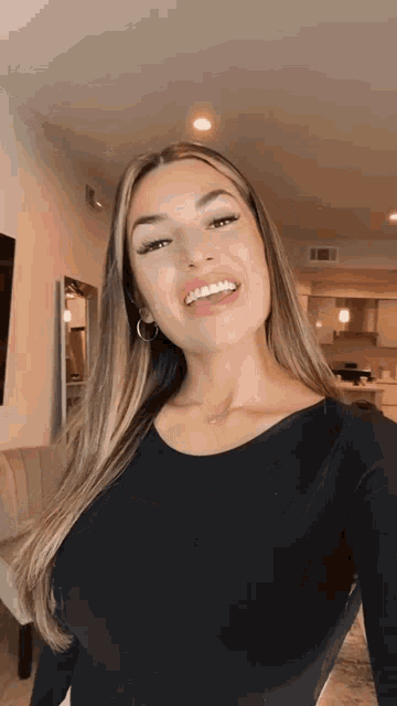 a woman wearing a black shirt is smiling and taking a selfie