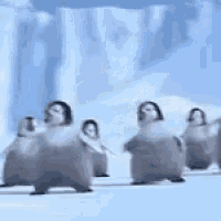 a row of penguins are walking in a line in the snow .