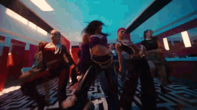 a group of women are dancing in a hallway in a room .