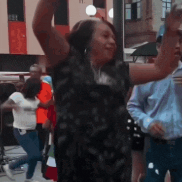 a woman in a black dress is dancing in the street