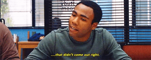 a man is sitting at a table in front of a window with blinds and talking to someone .