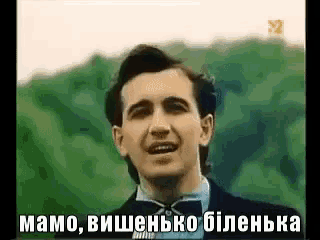 a man in a suit and bow tie is singing in a foreign language