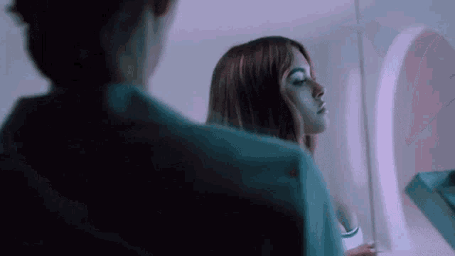 a woman is looking at her reflection in the mirror .