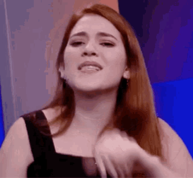 a woman with long red hair is making a funny face and holding her hair .