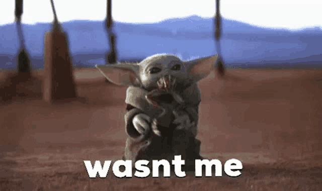 a baby yoda from the mandalorian is standing in the desert holding a snake and says `` wasnt me '' .