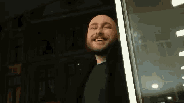 a man is looking out of a window with his head upside down and smiling .