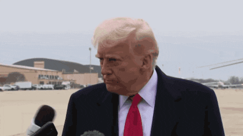 a man in a suit and red tie stands in front of a building that says ' donald ' on it