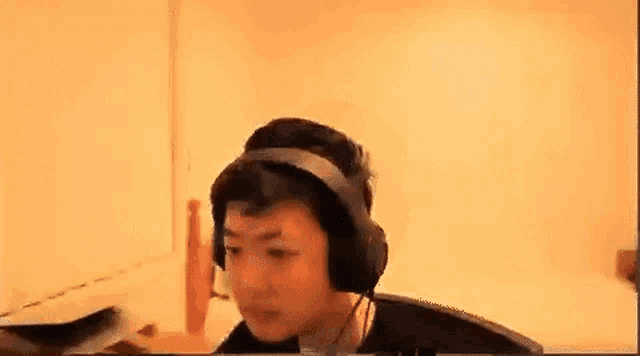 a man wearing headphones is sitting at a desk in front of a computer .