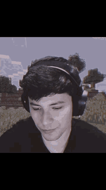 a man wearing headphones looks at the camera while playing minecraft