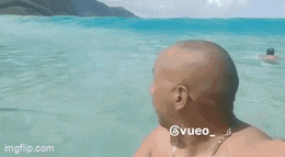 two bald men are swimming in the ocean and one has a ponytail on his head .