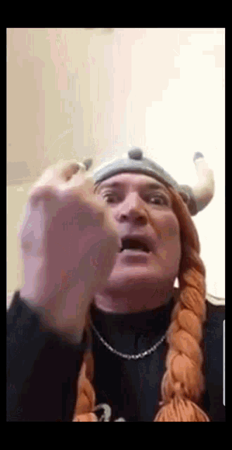a man wearing a viking hat and braids is pointing his finger