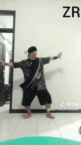a man is dancing in front of a white wall with the letters zr above him