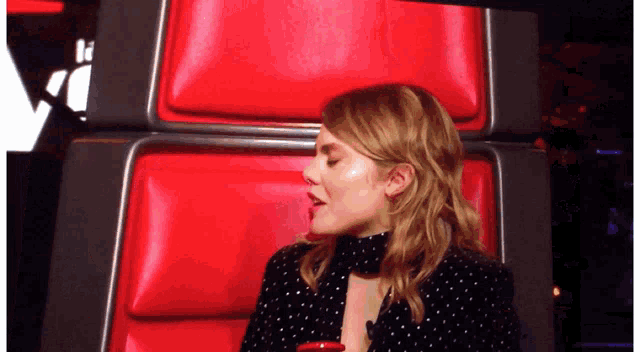 a woman is sitting in a chair with a red cushion