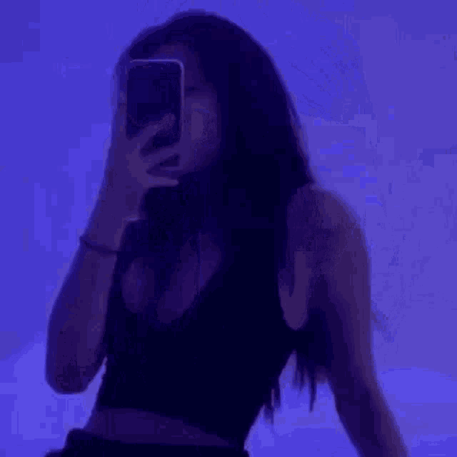 a woman is taking a selfie with her phone in a purple room .