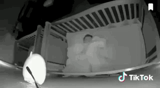 a baby is sleeping in a crib with a remote control .