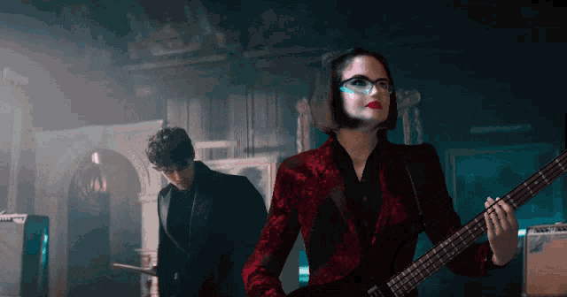 a woman in a red jacket is playing a guitar